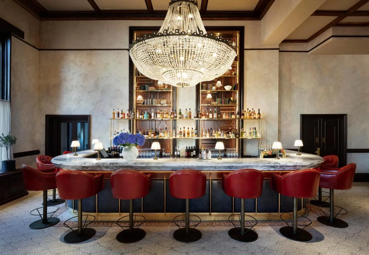 Bar with red chairs and a chandelier at The Randolph Hotel Oxford